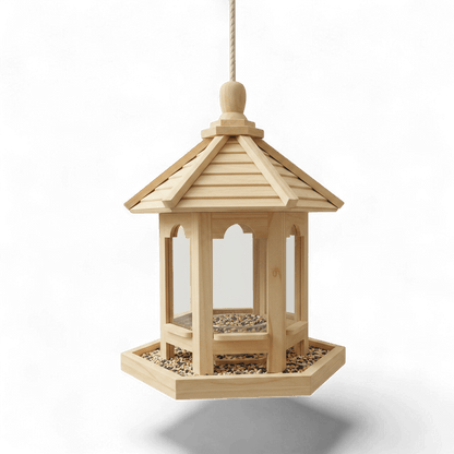 Mangeoire à oiseaux en bois clair style maisonnette gazebo hexagonal avec toit pointu et plateau rempli de graines, suspendue par une corde, sur fond blanc