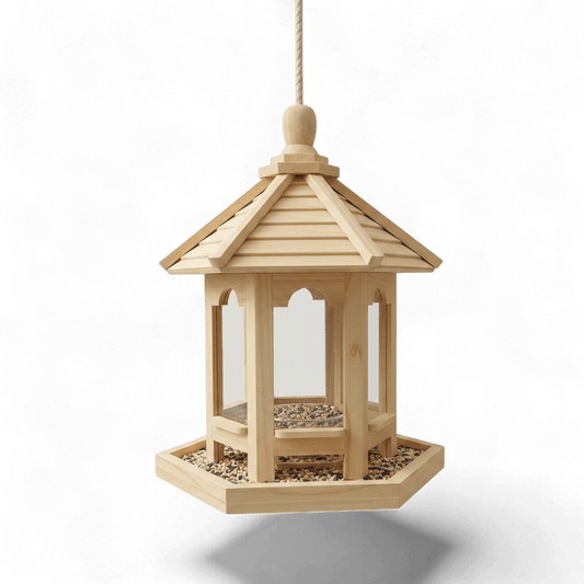Mangeoire à oiseaux en bois clair style maisonnette gazebo hexagonal avec toit pointu et plateau rempli de graines, suspendue par une corde, sur fond blanc